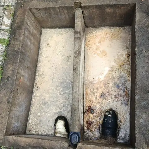 Caixa separadora de concreto de um comércio cheia de água com gordura antes da limpeza