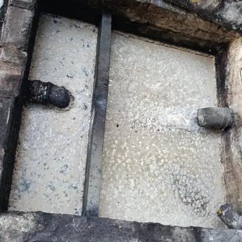 Caixa de concreto com duas câmaras coberta por gordura e espuma antes da limpeza