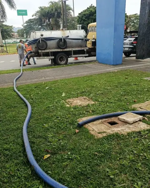 Caminhão limpa fossa da Desentupidora Meira atendendo em Joinville, com a mangueira estendida até a caixa de esgoto